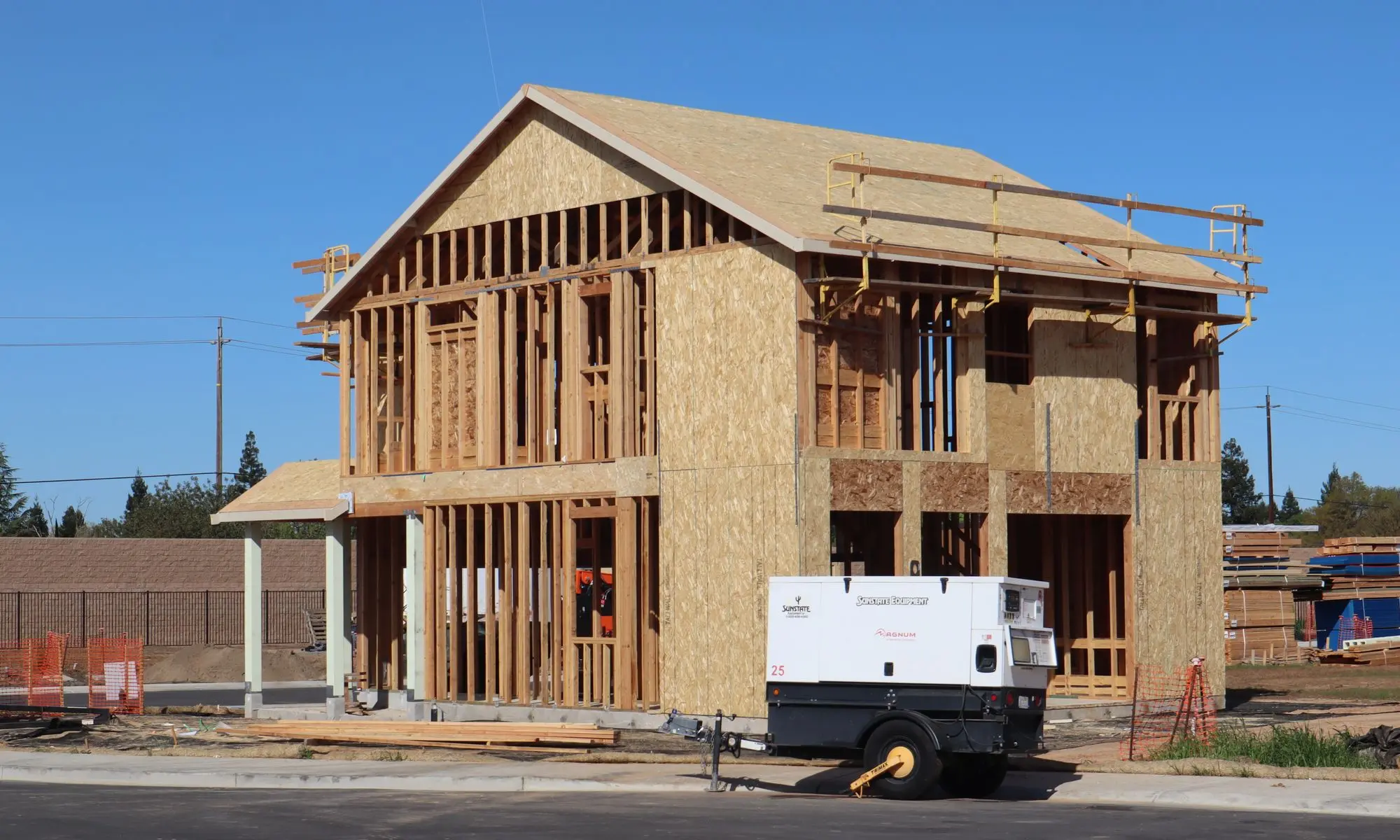 A newly framed house under construction in a suburban neighborhood